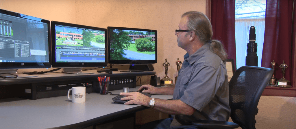 Picture of Robin at his workstation, surrounded by awards in the background from prior productions.